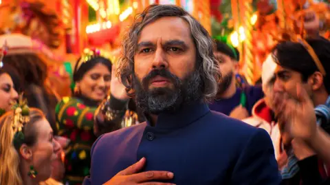 Christmas Karma Kunal Nayyar as a contemporary Scrooge, called Mr Sood, in a scene from Christmas Karma