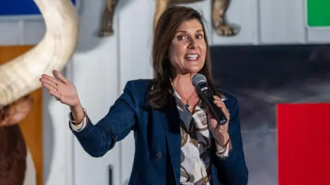 Getty Images Nikki Haley, wearing a blue blazer over a white shirt with red patterns, gestures with her right hand and speaks into a microphone held in her left hand as she introduces Senate candidate Dave McCormick at a rally in Pennsylvania