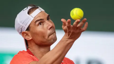 Rafael Nadal tosses up a ball during French Open practice