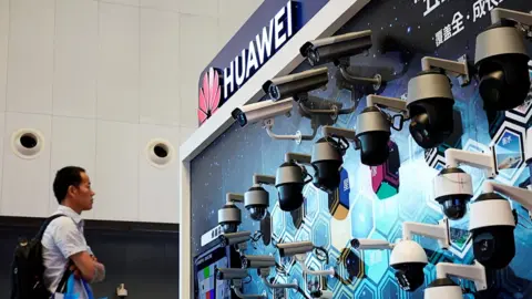 Reuters A man stands in front of a Huawei display of security cameras