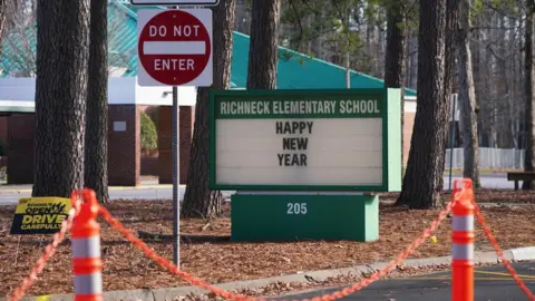 Getty Images A school sign wishing students a "Happy New Year" is seen outside Richneck Elementary School in Virginia, where authorities say a six-year-old shot their teacher.