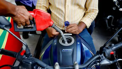 Reuters People refuel their motorcycles at a petrol station after fuel price surges up to 50%