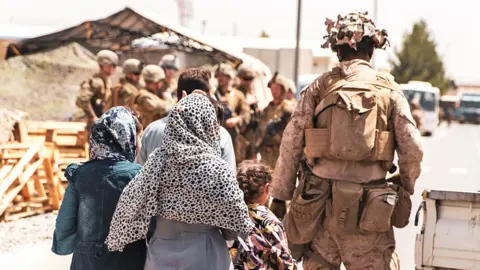 Reuters A US Marine escorts a family during an evacuation at Hamid Karzai International Airport, Kabul, Afghanistan, 21 August 2021