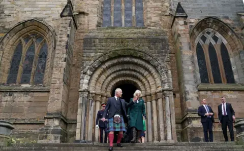 PA Media King Charles III, wearing a kilt, and the Queen Consort, in a green coat, leave Dunfermline Abbey, after a visit to mark its 950th anniversary in 2022.