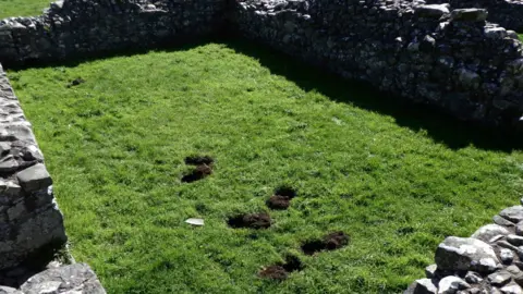 © Crown DfC Historic Environment Division Illegal metal detecting saw a number of large holes dug up at a medieval abbey site in County Down