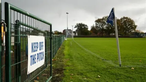 Shaun Whitmore/BBC A door that says: stay out of the field". A corner flag is in the foreground and the rest of the field in the background.