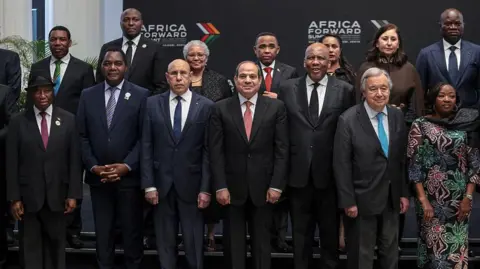 AFP via Getty Images Liberia's President Joseph Boakai, Zambia's President Hakainde Hichilema, Eswatini's Prime Minister Russell Dlamini, Mauritania's President Mohamed Ould Ghazouani, Egypt's President Abdel Fattah El-Sisi, UN Secretary General Antonio Guterres, Tunisia's Prime Minister Sarra Zaafrani, and Gabon's President Brice Oligui Nguema prepare to pose for a photo