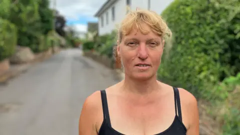 Woman standing in village road with cottages in the background