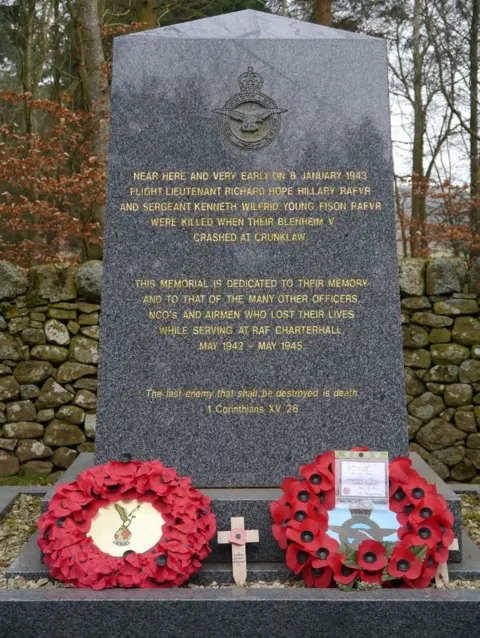 James Towill A large memorial with gold typeface on black marble and two poppy wreaths lying on top of it