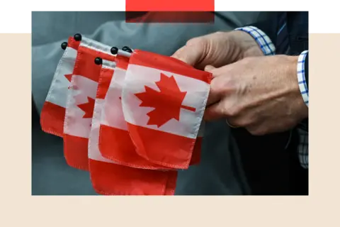 Getty Images Small Canadian flags held in a hand