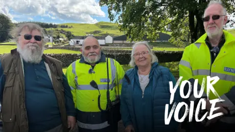 BBC An up-to-date image of the four friends, Ross, Tom, Anne and William. A field and a farm are behind the row of four and the sun is shining. 