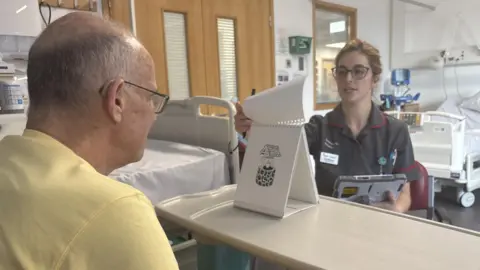 A Dementia Research Nurse turns a flip chart of images for a clinical trial participant to identify.
