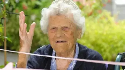 Hallmark Care Homes Close up shot of Ethel Catherham wearing a tiara with 115 written on it.