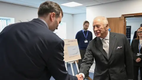PA Media King Charles III shakes hands with a staff member during a visit to Oxford Photovoltaics Limited (Oxford PV), a trailblazing Oxfordshire enterprise developing advanced solar panels capable of converting more of the sun's spectrum into clean, affordable energy.