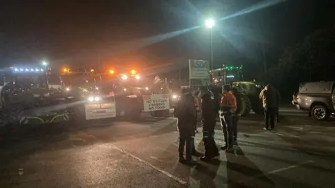 Tractors parked across a road at night
