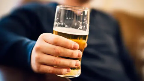 Getty Images Man holding a pint glass