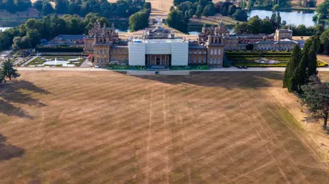 The outline of a former garden can be seen on a lawn in front of the immense Blenheim Palace structure.