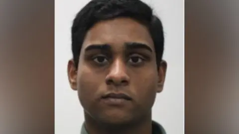 Dihan Rahman - a young man with short, black hair looks into a camera for a police custody shot