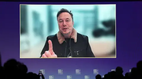 Elon Musk, chief executive officer of Tesla Inc., speaks via video link at the Qatar Economic Forum (QEF) in Doha, Qatar, on Tuesday, May 20, 2025. 