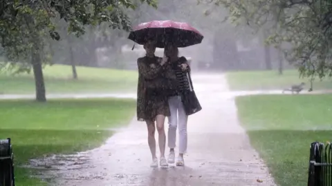 PA Media Two women walking in rain