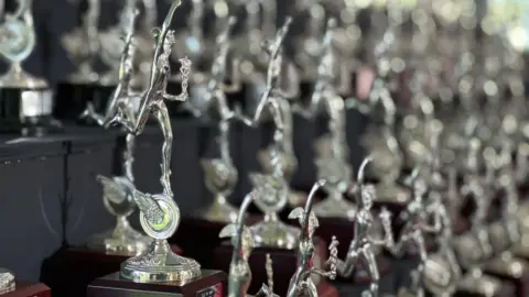 Rows of silver replicas on a graduated stand in the exhibition.