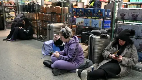 Getty Images Passengers wait with their luggage at St Pancras station