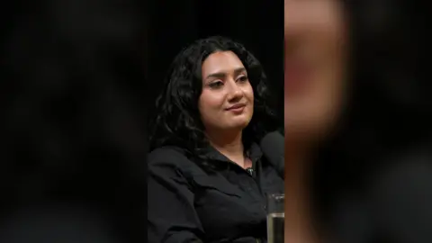 Shaheen Hashmat has long dark hair and is wearing a black shirt