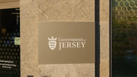 A beige sign that reads Government of Jersey on the side of a building.