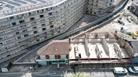 Environment Agency An ariel view shows housing developments being built on both sides of the brook with new flood walls visible either side of it.