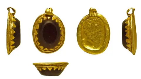 The Portable Antiquities Scheme Five views of an Anglo-Saxon oval gold and gemstone pendant. The dark, flat-topped gem, possibly a garnet is set within a hammered gold frame, with a hanging loop at its top end. The four top views show the pendant's left side, the front showing the gemstone, the back which is plain gold and the right side. The final view, beneath the others, is of a side view of the pendant from its base. 