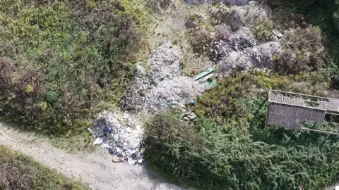 Maidstone Borough Council An aerial view of a large pile of illegally dumped waste on a plot of land.
