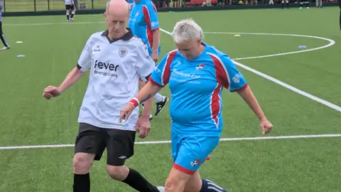 Phil Lindley A man and a woman are playing football next to eachother