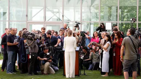 Getty Images Sussan Ley, wearing a cream suit, surrounded by a press park in the parliament courtyard