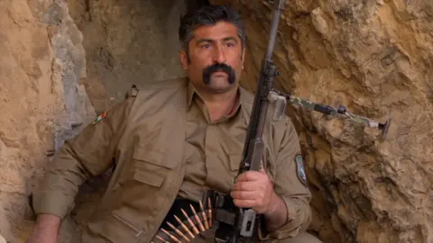 A Kurdish Pershmerga fighter in a cave with a gun