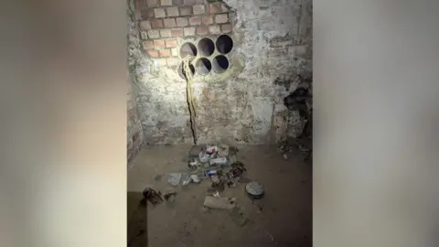 RSPCA Ropes are seen coming out of one of six pipes leading into an old cellar. There is a pile of rubbish on the concrete floor of the cellar