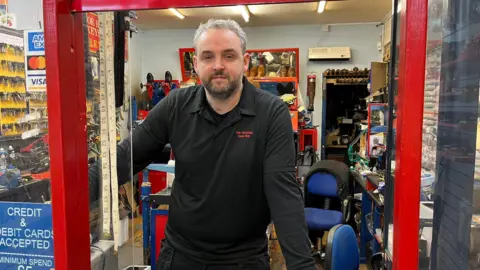 A man in a worksop wearing a black polo neck top.