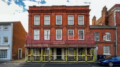 An exterior view of the Museum of Farnham, a red brick building, surrounded by scaffolding poles.