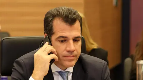 EPA Greece's migration and asylum minister Thanos Plevris taking a phone call while seated inside.