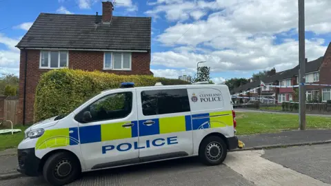 BBC A police van parked outside a house.