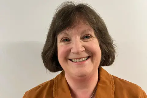 A woman with dark hair smiles into the camera