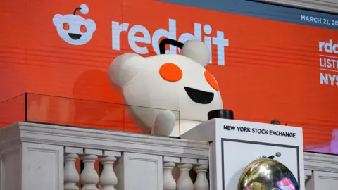 Reddit mascot rings New York Stock Exchange opening bell.