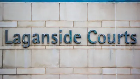 A stone building with the words Laganside Courts is written in silver writing on the side. 