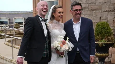 PA Media Prime Minister Andy Burnham meets bride and groom Conor, from Belfast and Kira, from Liverpool, Rosato, as he arrives at the Culloden Hotel, Belfast, during his first visit to Northern Ireland.