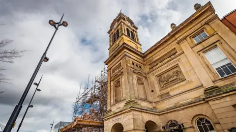 The light coloured stone of the Guildhall Theatre building with scaffolding over part of it