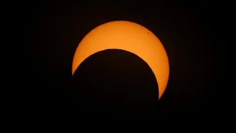 The moon passes the sun during an annular solar eclipse, in Las Horquetas, Santa Cruz, Argentina. The orange sun looks like a "C" on its side as the moon passes it.