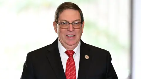 Getty Images Bruno Rodríguez wearing a dark suit, white shirt and red patterned tie.