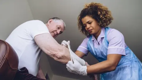 Getty Images Carer helping man