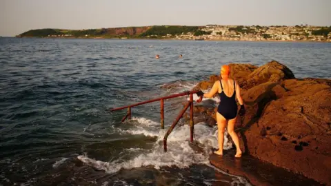 Ben Birchall/PA People preparing to enter the water in Penzance, Cornwall