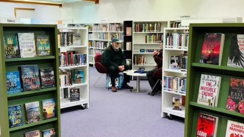 People sitting at a table in a library, surrounded by books