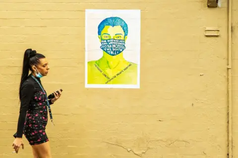 Getty Images A woman is seen walking past a political poster on March 26, 2020 in Sydney, Australia.